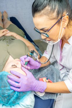 Güzel bir kadın kozmetoloji salonunda kalıcı makyaj yapıyor..