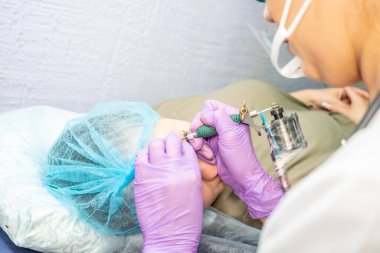 Güzel bir kadın kozmetoloji salonunda kalıcı makyaj yapıyor..