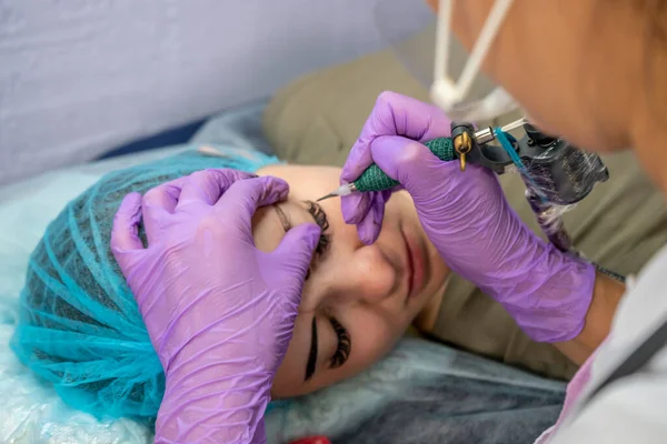 Güzel bir kadın kozmetoloji salonunda kalıcı makyaj yapıyor..