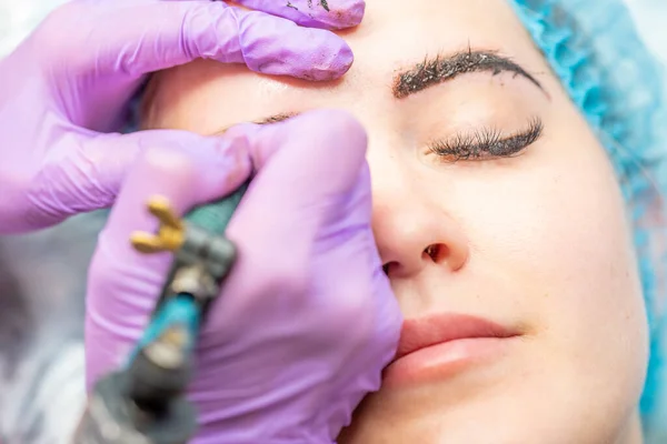 Güzel bir kadın kozmetoloji salonunda kalıcı makyaj yapıyor..