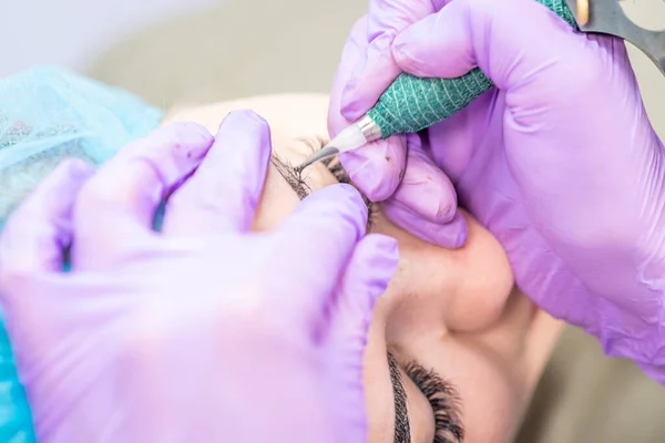 Güzel bir kadın kozmetoloji salonunda kalıcı makyaj yapıyor..