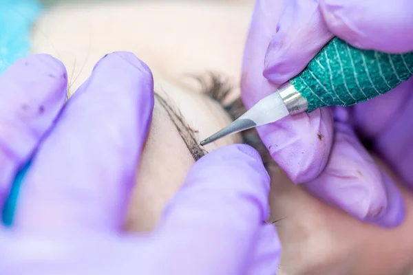 Güzel bir kadın kozmetoloji salonunda kalıcı makyaj yapıyor..