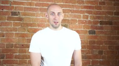 Tuğla duvarın önünde duran bir adam.