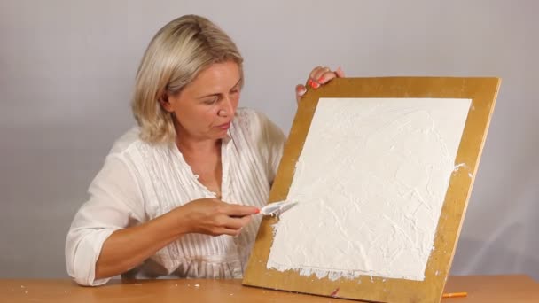 Aplicando um gesso texturizado branco artístico com uma pequena faca de paleta de metal — Vídeo de Stock