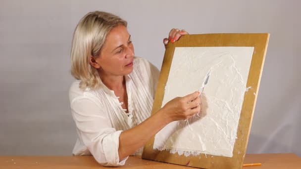 Aplicando um gesso texturizado branco artístico com uma pequena faca de paleta de metal — Vídeo de Stock