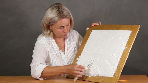 Aplicando um gesso texturizado branco artístico com uma pequena faca de paleta de metal — Vídeo de Stock