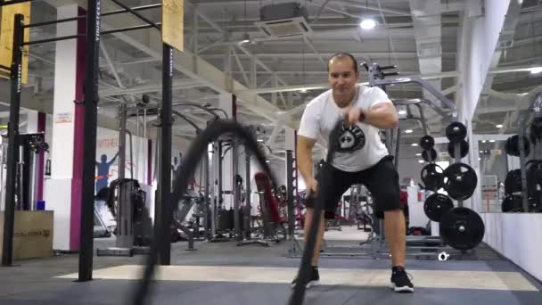No ginásio crossfit homem leva duas cordas e executa um exercício de poder . — Vídeo de Stock