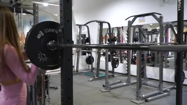 Gadis muda ceria jongkok dengan barbel di gym — Stok Video