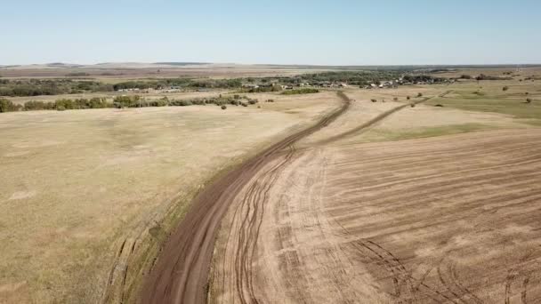 El camino a través de los campos que conducen a un pequeño pueblo. — Vídeo de stock