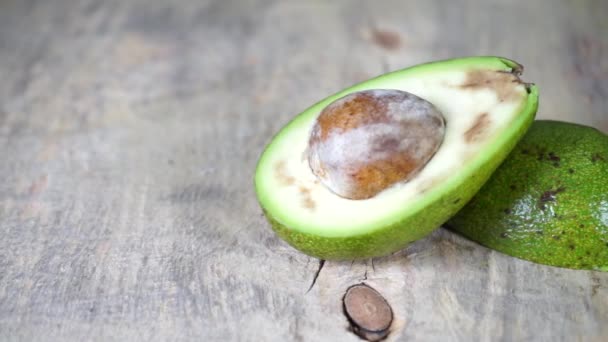 Fruta de aguacate maduro fresco verde cortada en una mesa de madera — Vídeos de Stock