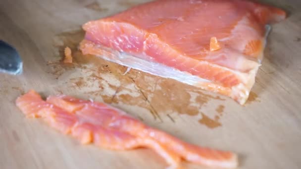 Affettare il salmone con un coltello di metallo con un manico di legno su una superficie di legno — Video Stock