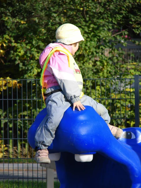 Het kind zit op blauwe hippopotamus in park — Stockfoto
