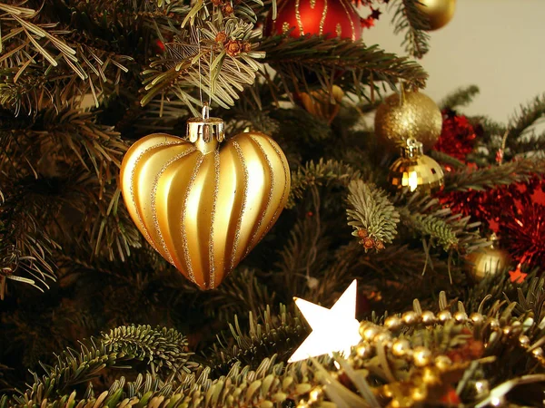 The gold heart hangs on Christmas tree Stock Photo
