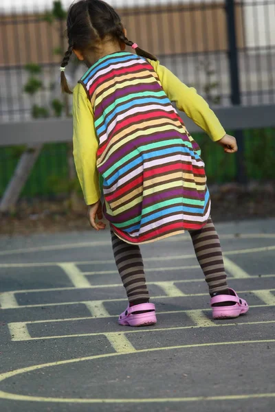 Дівчина в смугастій сукні грає на ігровому майданчику — стокове фото