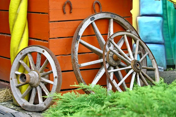 Vecchia ruota di carro in legno appoggiata alla parete di legno — Foto Stock