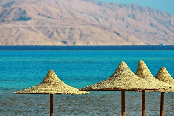 Paraplyer och Röda havet på berget bakgrund — Stockfoto