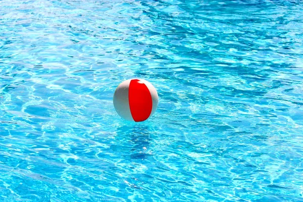 Balle de plage flottant dans une piscine avec de petites vagues réfléchissant au soleil d'été — Photo