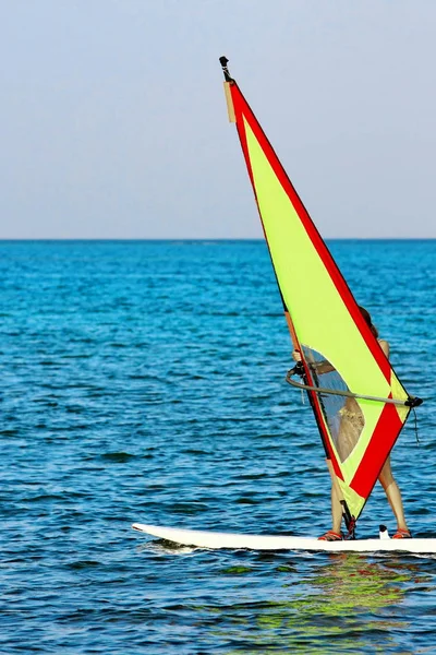 Windsurfer, blue sea and yellow sail. Surfer exercising in calm sea or ocean — Stock Photo, Image