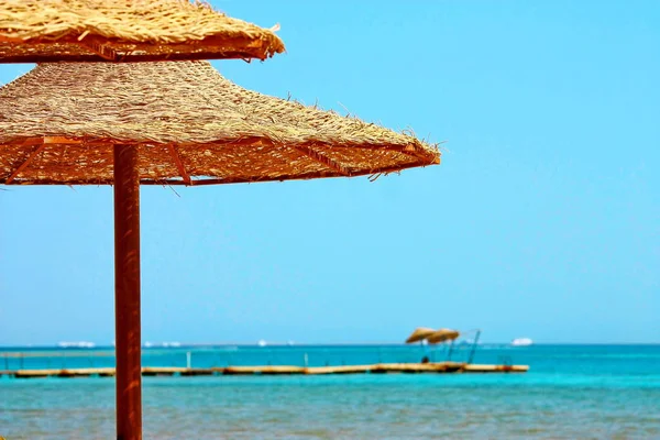 Sonnenschirme und rotes Meer auf blauem Himmel Hintergrund — Stockfoto