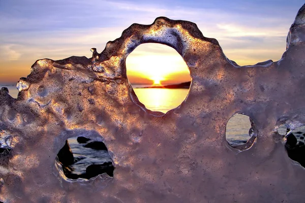 Uitzicht op de zonsondergang in de winter door gaten in het ijs — Stockfoto