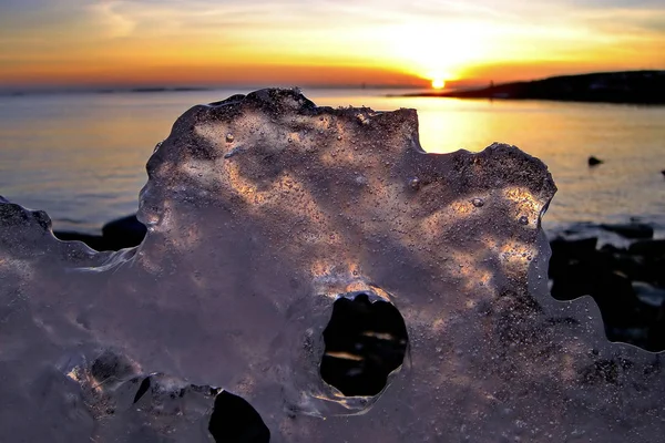 Uitzicht op de zonsondergang in de winter door gaten in het ijs — Stockfoto