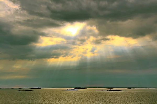 Solen bakom molnen med strålar av ljus som skiner ner på havet — Stockfoto