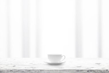 Bir arka plan üzerinde ahşap masa ve pencere perde üzerinde sıcak içecekle Kupası