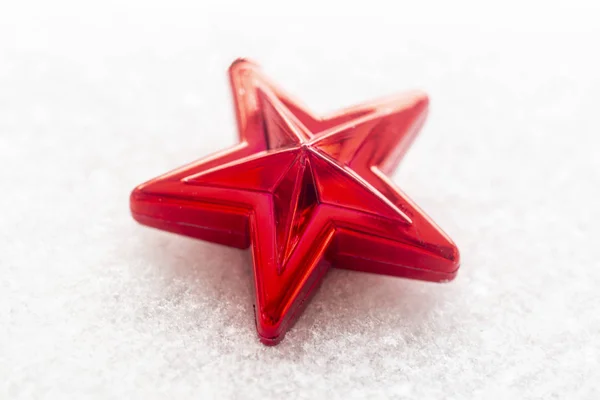 Christmas toy red star on snow-covered wooden background