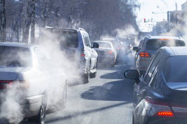 Kışın şehirde araba egzozundan kaynaklanan kirlilik. Soğuk bir kış gününde arabalardan duman çıkıyor.
