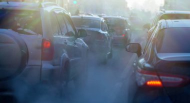Kışın şehirde araba egzozundan kaynaklanan kirlilik. Soğuk bir kış gününde arabalardan duman çıkıyor.