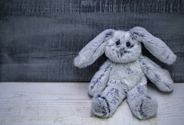 soft toy rabbit made of faux fur on grey wooden background