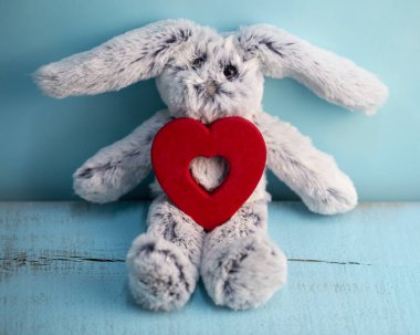 kalp mavi ahşap arka plan üzerinde gri pelüş tavşan