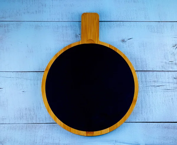 round graphite cutting cooking Board on wooden surface, top view