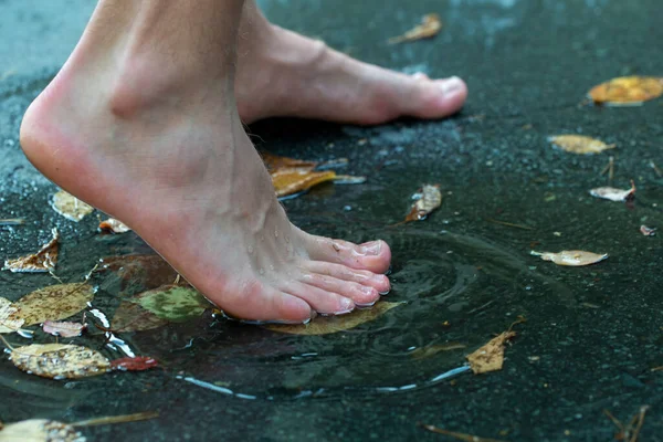 teen walks through puddles after summer rain, feet in a puddle