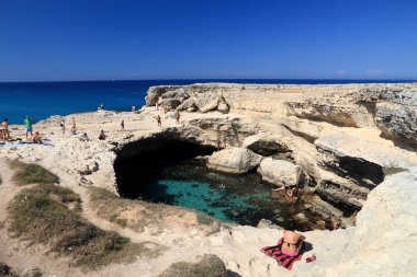 SALENTO, İtalya - 1 Haziran 2017 İnsanlar İtalya 'nın Salento Yarımadası, Roca' daki Grotta Della Poesia yüzme mağarasını ziyaret ediyor. Yıllık 50 milyon ziyaretçiyle İtalya, en çok ziyaret edilen ülkelerden biri oldu..