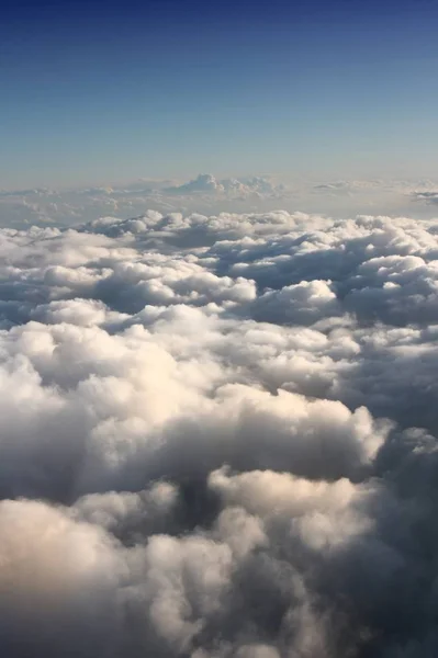 Fluffy clouds aerial view. White cumulus clouds sky view from airplane.