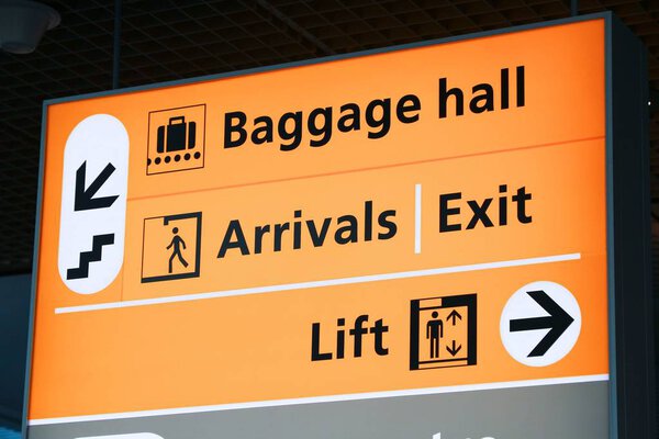 Generic airport signage in Amsterdam. Illuminated sign. Baggage hall, arrivals and exit.