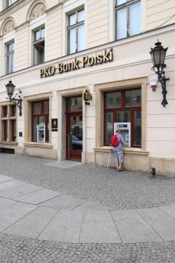 WROCLAW, POLAND - MAY 11, 2018: Person uses ATM of PKO Bank Polski branch in Wroclaw, Poland. PKO Bank Polski is the largest bank in Poland by assets and number of branches. clipart