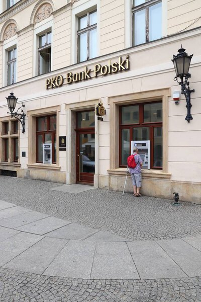 WROCLAW, POLAND - MAY 11, 2018: Person uses ATM of PKO Bank Polski branch in Wroclaw, Poland. PKO Bank Polski is the largest bank in Poland by assets and number of branches.