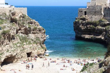POLİGNANO A MARE, İtalya - 29 Mayıs 2017: İnsanlar İtalya 'nın Apulia kentindeki eşsiz Polignano a Mare plajını ziyaret ediyor. Yıllık 50 milyon ziyaretçiyle İtalya, en çok ziyaret edilen ülkelerden biri oldu..