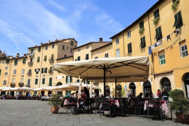 Lucca, İtalya - 29 Nisan 2015: İnsanlar eski şehir Meydanı (Piazza Anfiteatro veya amfi tiyatro kare) Lucca, İtalya ziyaret edin. İtalya bir yıl (2013 47,7 milyon turist tarafından ziyaret edilmiştir).