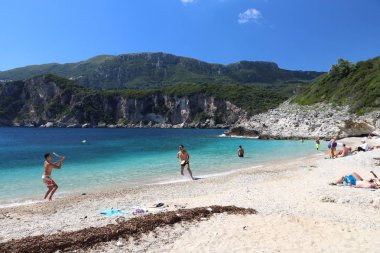 CORFU, GREECE - 2 Haziran 2016: İnsanlar Yunanistan 'ın Corfu Adası' ndaki Rovinia plajını ziyaret ediyor. 2012 yılında Korfu 'yu 558 bin turist ziyaret etti.