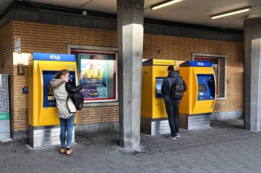 EINDHOVEN, NETHERLANDS - 19 Kasım 2016: Eindhoven, Hollanda 'daki tren istasyonundan bilet alan yolcular. Bilet makineleri Nederlandse Spoorwegen (Hollanda Demiryolları).