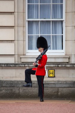 LONDON, İngiltere - 23 Nisan 2016: Kraliçe 'nin Muhafızları Londra, İngiltere' deki Buckingham Sarayı önünde devriye geziyor. Geleneksel üniformalı muhafızlar İngiltere 'nin önemli bir sembolüdür..