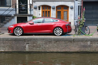 AMSTERDAM, NETHERLANDS - 10 Temmuz 2017: Amsterdam 'da kanal tarafından şarj edilen elektrikli Tesla Model S arabası. Hollanda 'da 1.000 kişi başına 528 kayıtlı araç var..