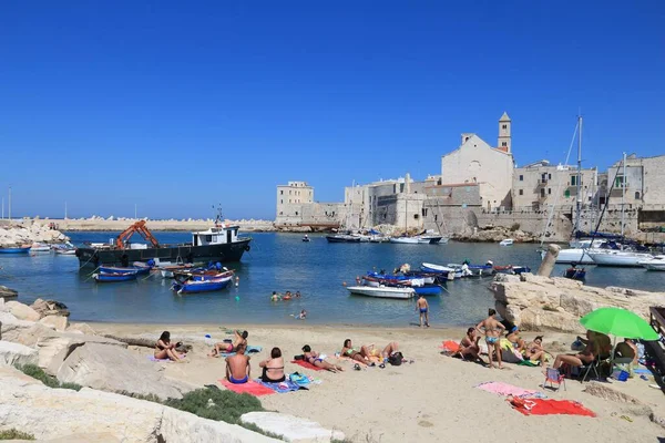 GIOVINAZO, İtalya - 28 Mayıs 2017: İnsanlar İtalya 'nın Apulia bölgesindeki Giovinazzo plajını ziyaret ediyor. Yıllık 50 milyon ziyaretçiyle İtalya, en çok ziyaret edilen ülkelerden biri oldu..