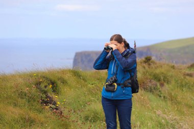Dürbün kullanarak bir uçurumun tepesindeki kuş gözlemcisi. Yazın Moher Kayalıkları. İrlanda doğa hedefi.