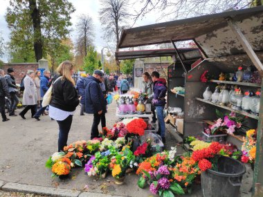 CHORZOW, POLAND - 1 Kasım 2023: İnsanlar Polonya 'da Azizler Günü' nde (Wszystkich Swietych) bir mezarlıktan mumlar ve yapay çiçek süslemeleri satın alıyorlar.