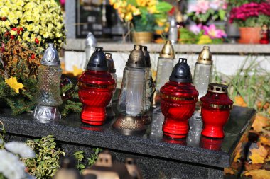 Polonya 'nın Varşova kentindeki All Saints Günü' nde (Wszystkich Swietych) bir mezarlıkta yağmur suyunun onu yıkamasına izin vermek için mezar yüzeyini eğimli veya eğimli hale getirmek.