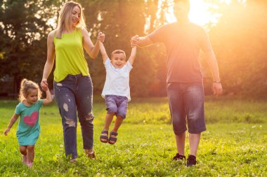 Aile, mutluluk, çocukluk ve insanlar kavramı - çim parkta oynarken mutlu genç Aile